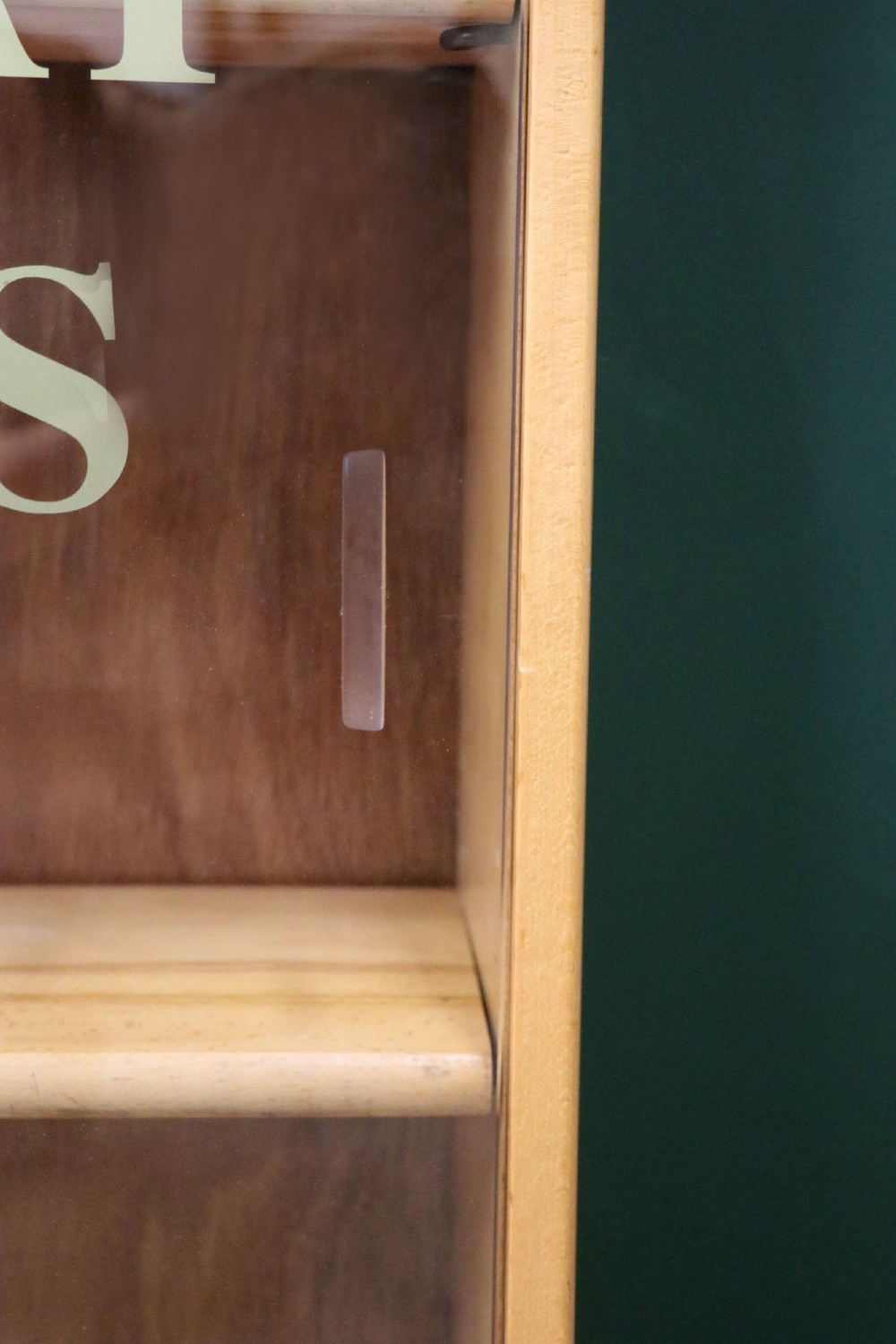 A low mid-century light oak bookcase with sliding glass doors featuring printed gold typography reading The Times and The Sunday Times London. View XI