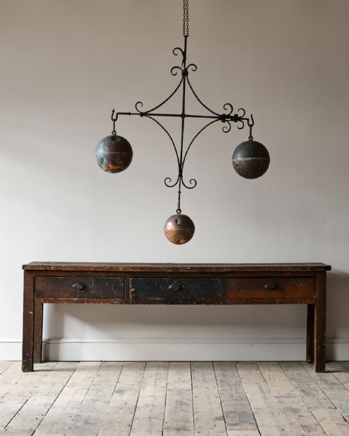 fig 1. A 19th-century wrought iron framework featuring scrollwork and supporting three suspended copper spheres.