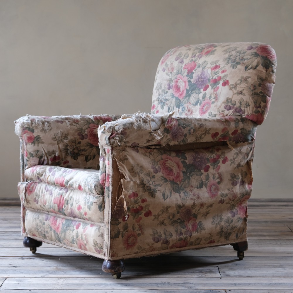 An early 20th-century upholstered armchair featuring floral chintz fabric, a deep seat cushion, turned wooden front legs, and brass castors. View II