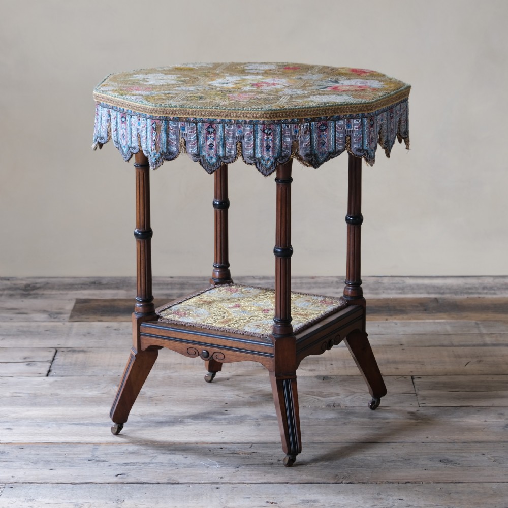 A 19th-century octagonal Aesthetic Movement side table with turned ebonised legs, a lower shelf, and a beaded tapestry top.