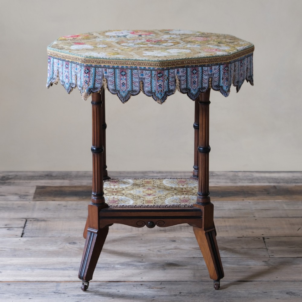 A 19th-century octagonal Aesthetic Movement side table with turned ebonised legs, a lower shelf, and a beaded tapestry top. View II