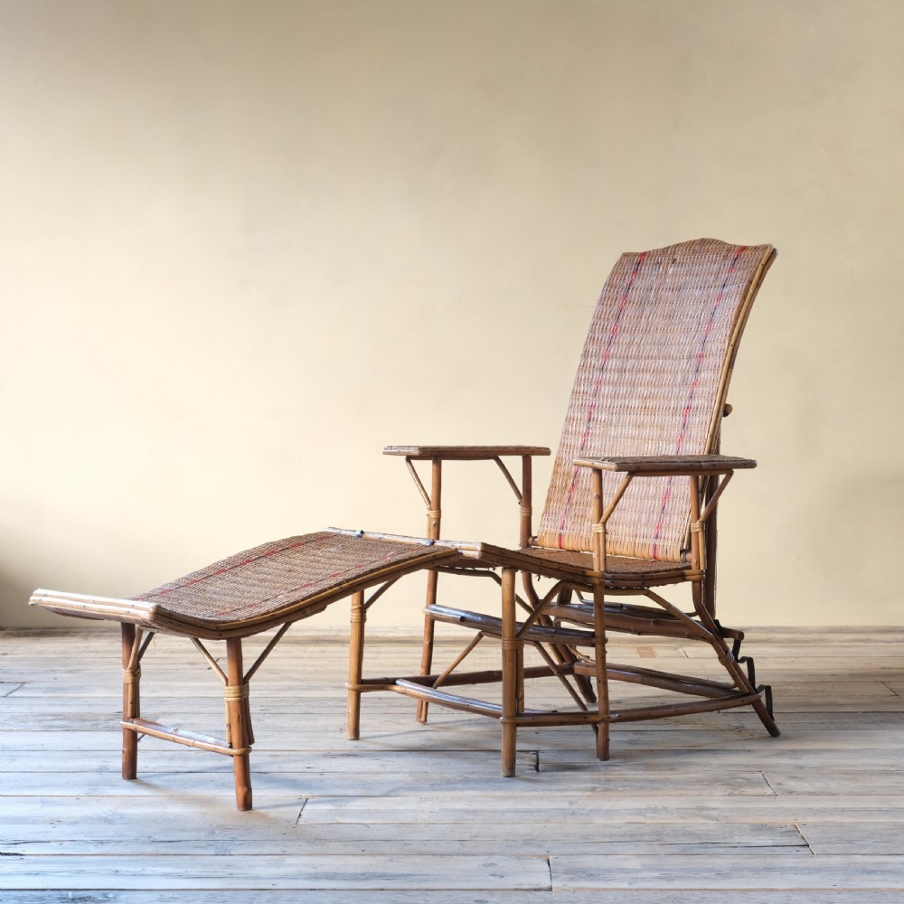 An antique French bamboo reclining chaise longue with a woven cane seat, raised armrests, and extending footrest. View IV