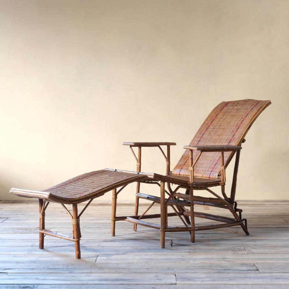 An antique French bamboo reclining chaise longue with a woven cane seat, raised armrests, and extending footrest. View V