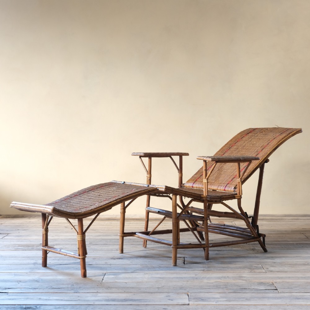 An antique French bamboo reclining chaise longue with a woven cane seat, raised armrests, and extending footrest. View VI