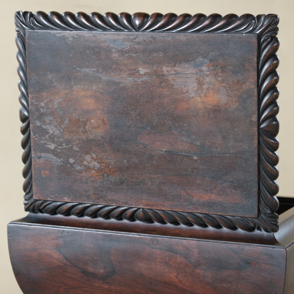 A dark rosewood Regency teapoy featuring gadrooned moulding, a carved column pedestal, and four scrolled legs. View IV