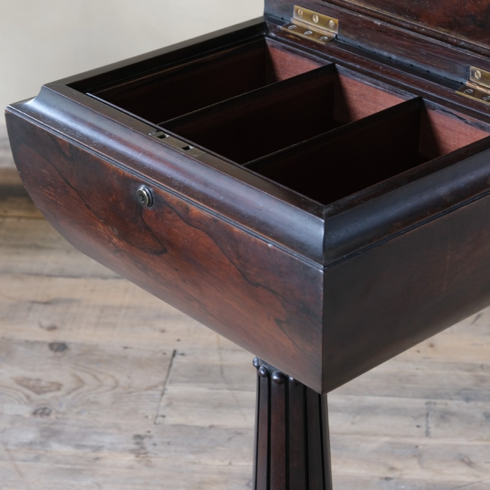 A dark rosewood Regency teapoy featuring gadrooned moulding, a carved column pedestal, and four scrolled legs. View V