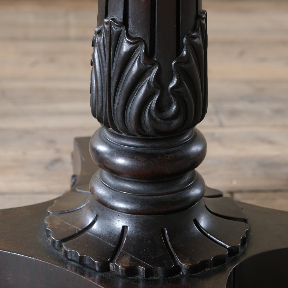 A dark rosewood Regency teapoy featuring gadrooned moulding, a carved column pedestal, and four scrolled legs. View VI
