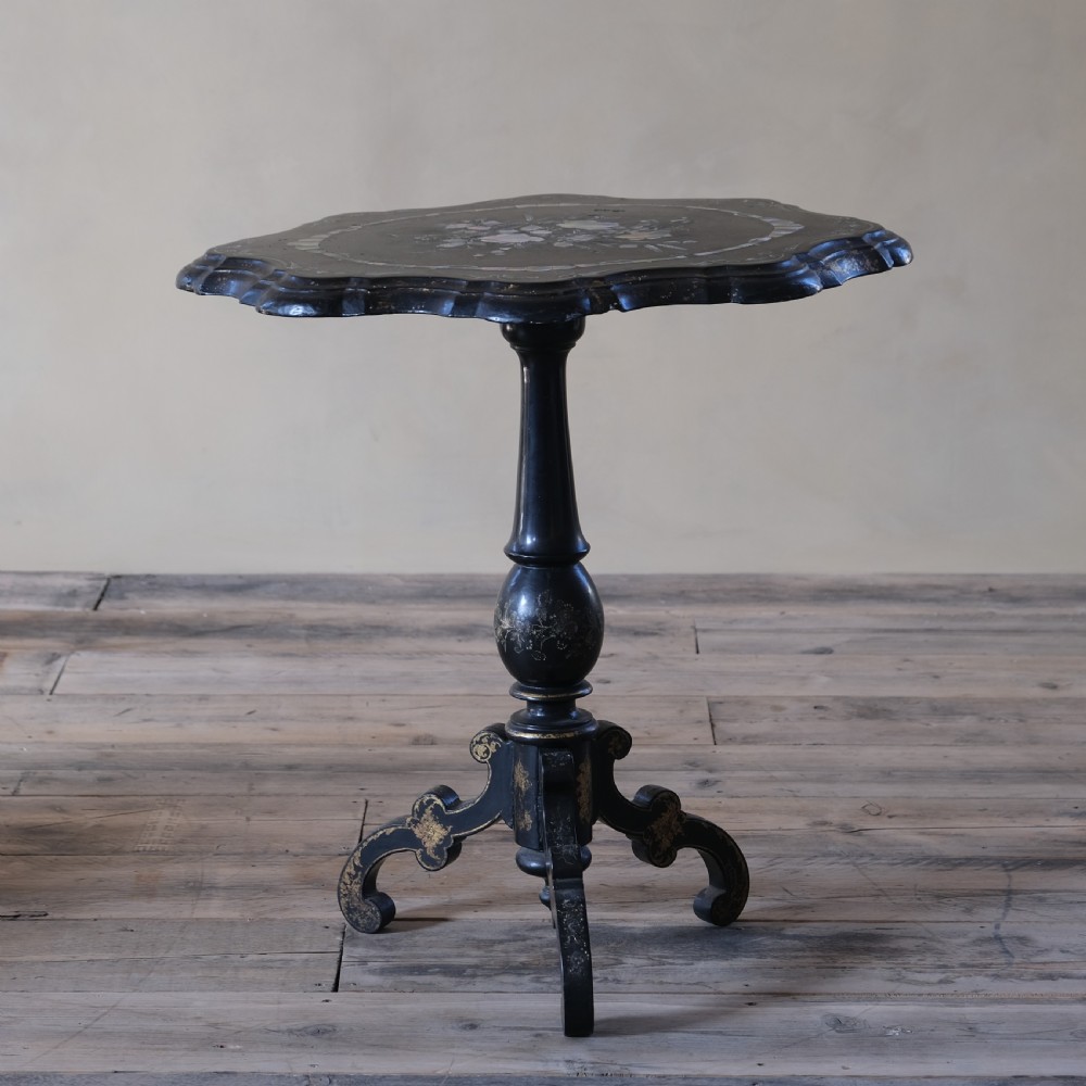 A 19th-century black lacquer papier-mache side table featuring a scalloped floral inlaid top on a turned pedestal with scroll feet.
