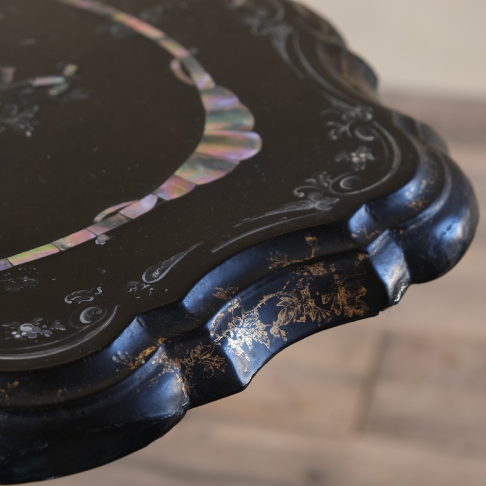 A 19th-century black lacquer papier-mache side table featuring a scalloped floral inlaid top on a turned pedestal with scroll feet. View IV
