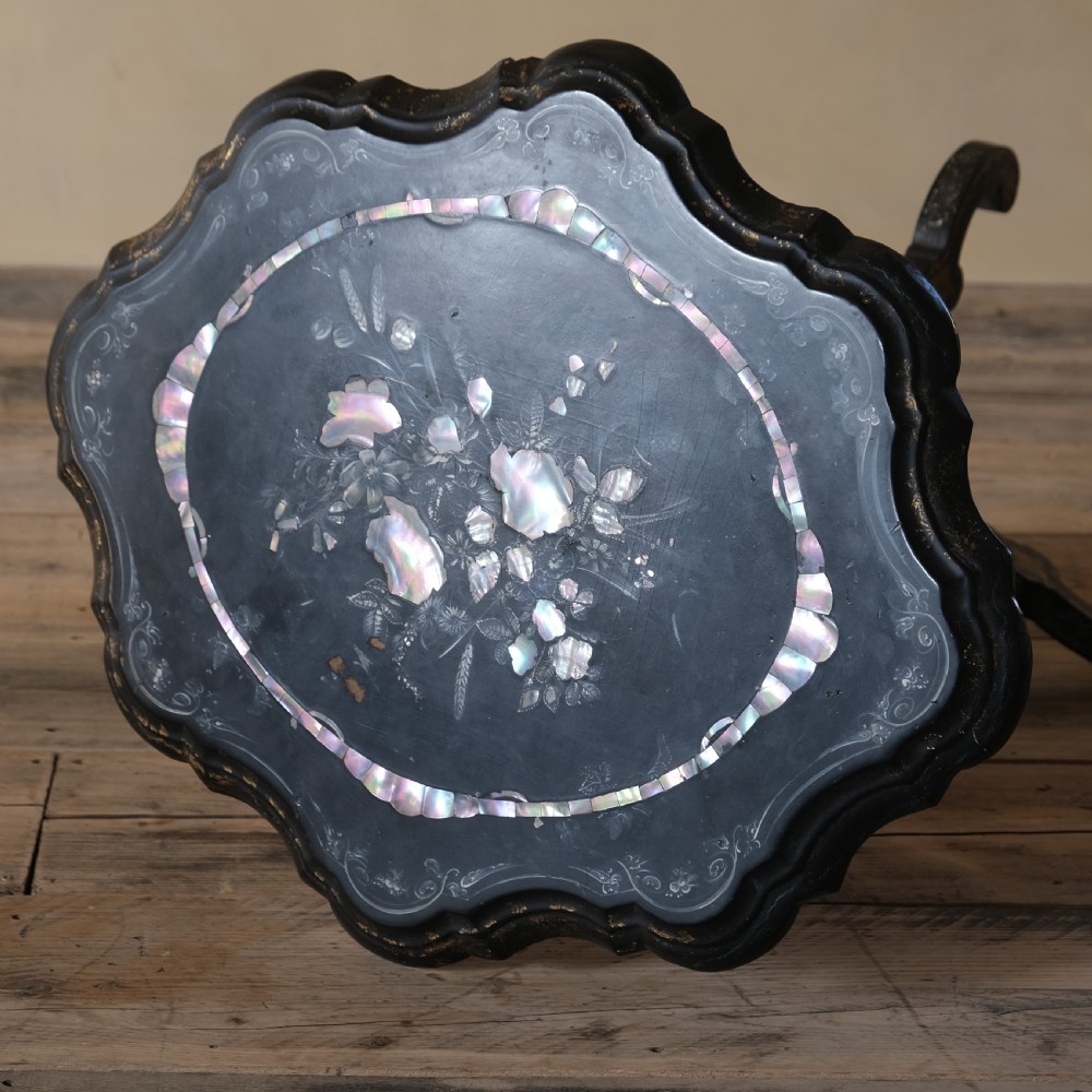 A 19th-century black lacquer papier-mache side table featuring a scalloped floral inlaid top on a turned pedestal with scroll feet. View VI