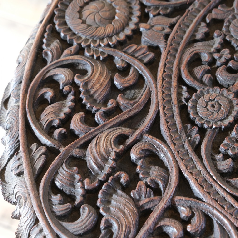 A late 19th-century Burmese dark teak two-tier side table with hand-carved mythological figure supports and circular foliate-carved surfaces. View VII