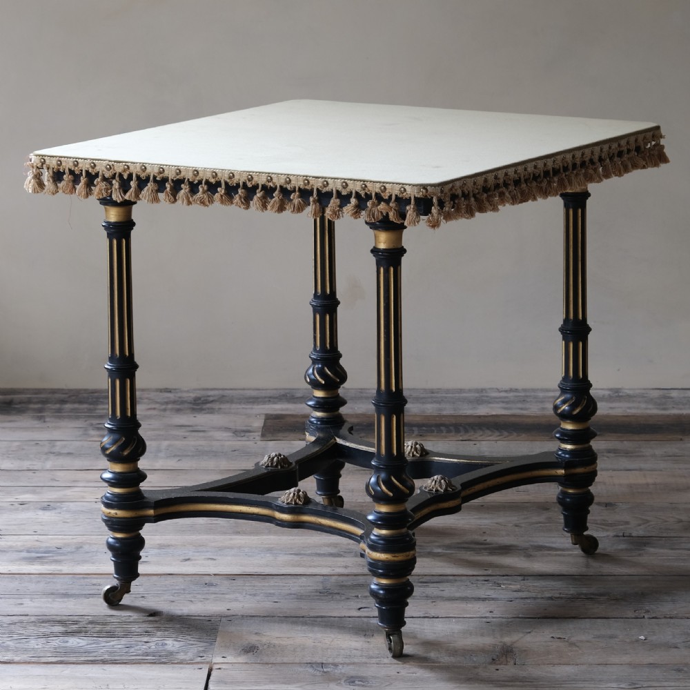 An Aesthetic Movement ebonised and parcel-gilt square table featuring fluted turned legs, a tassel fringe skirt, and brass castors. View III