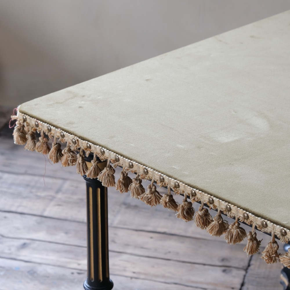 An Aesthetic Movement ebonised and parcel-gilt square table featuring fluted turned legs, a tassel fringe skirt, and brass castors. View V