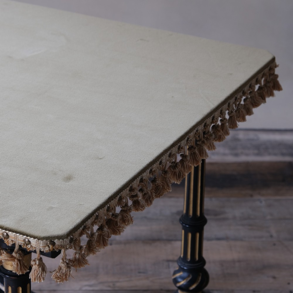 An Aesthetic Movement ebonised and parcel-gilt square table featuring fluted turned legs, a tassel fringe skirt, and brass castors. View VI