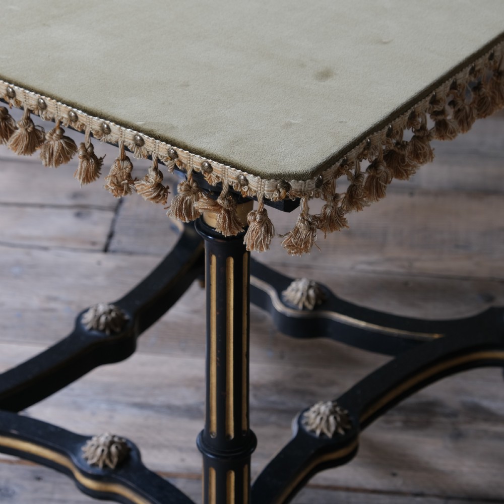 An Aesthetic Movement ebonised and parcel-gilt square table featuring fluted turned legs, a tassel fringe skirt, and brass castors. View VII