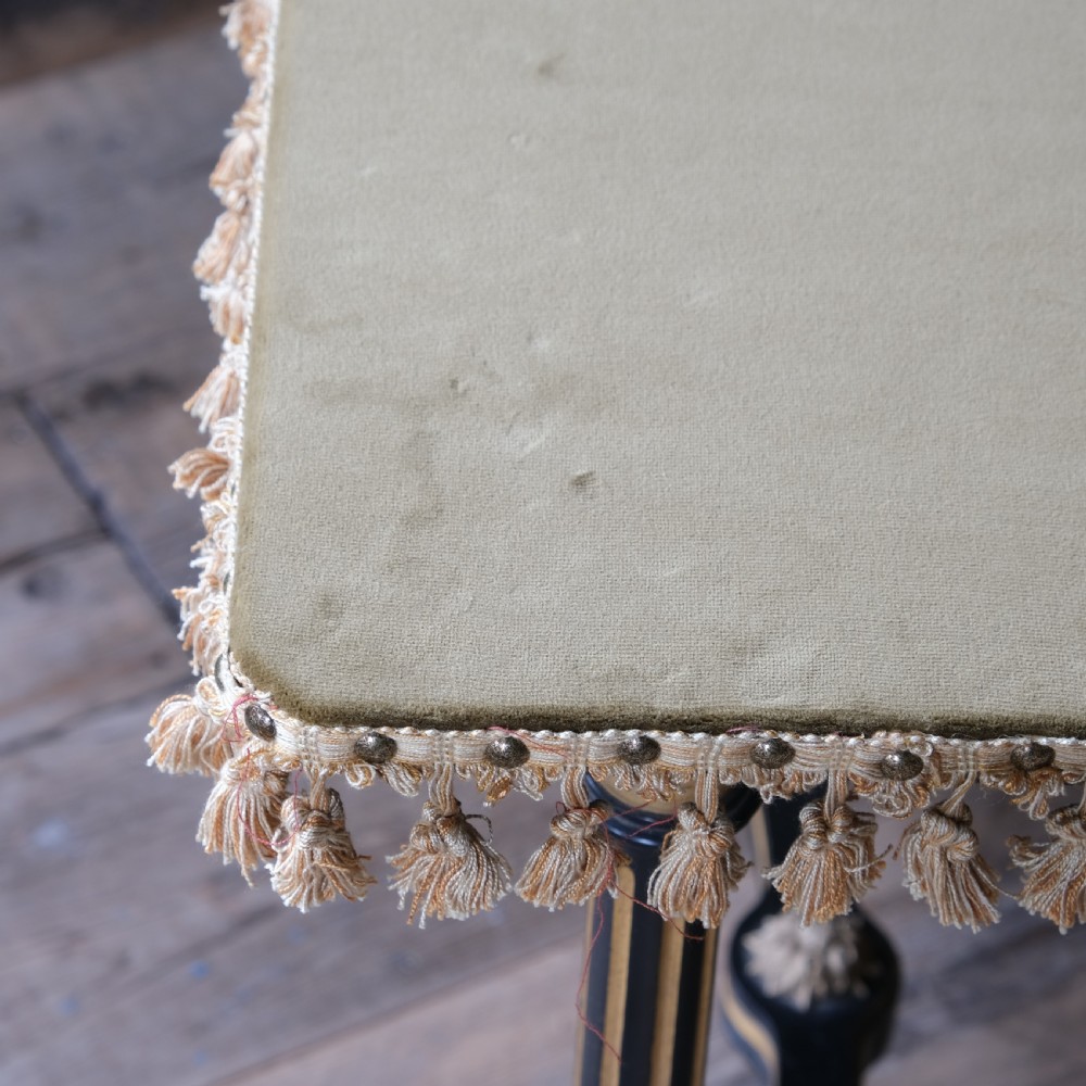 An Aesthetic Movement ebonised and parcel-gilt square table featuring fluted turned legs, a tassel fringe skirt, and brass castors. View X