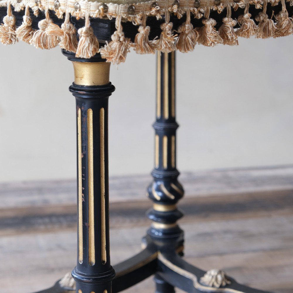 An Aesthetic Movement ebonised and parcel-gilt square table featuring fluted turned legs, a tassel fringe skirt, and brass castors. View XI