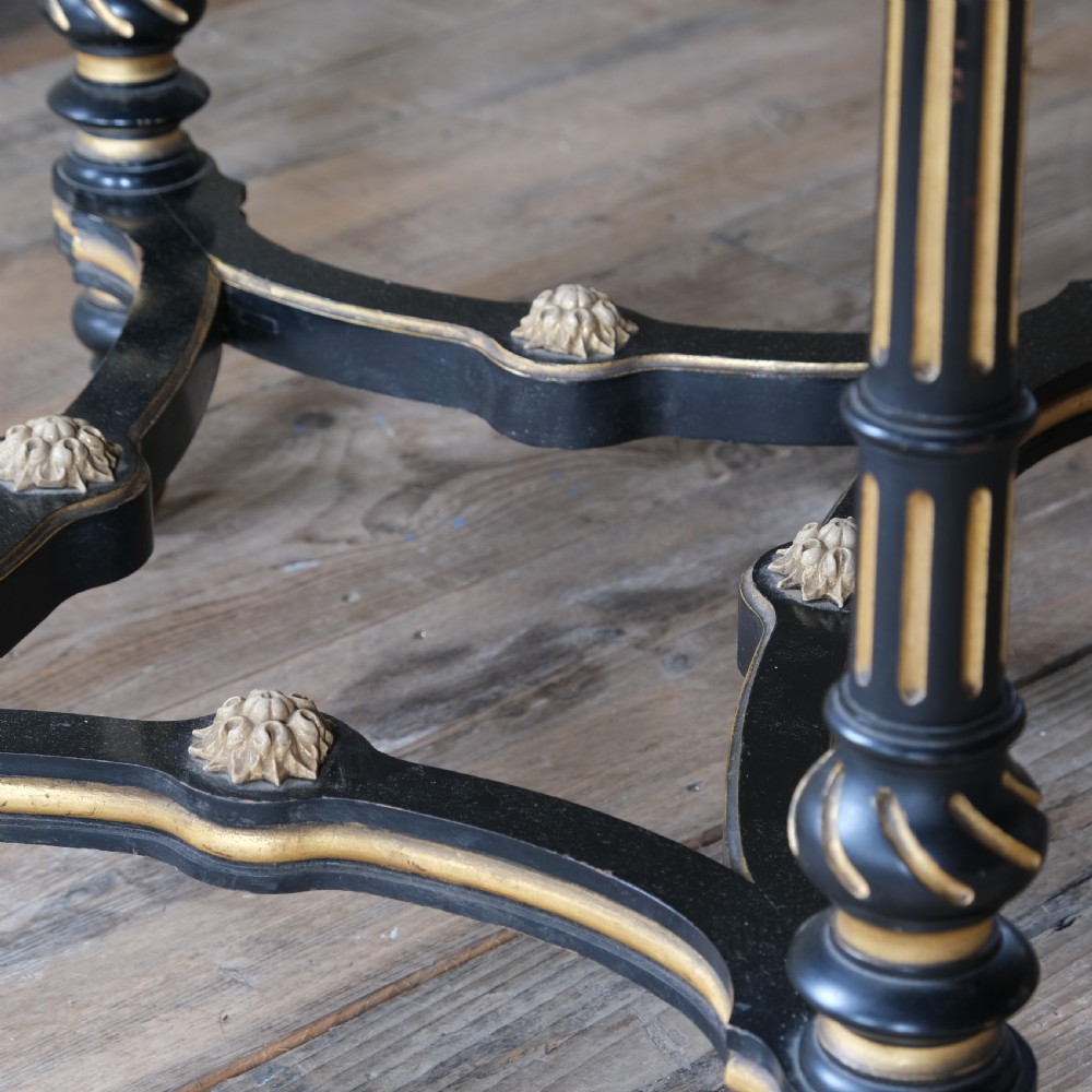 An Aesthetic Movement ebonised and parcel-gilt square table featuring fluted turned legs, a tassel fringe skirt, and brass castors. View XIV