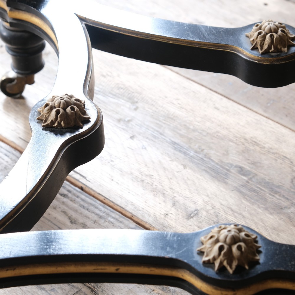 An Aesthetic Movement ebonised and parcel-gilt square table featuring fluted turned legs, a tassel fringe skirt, and brass castors. View XV