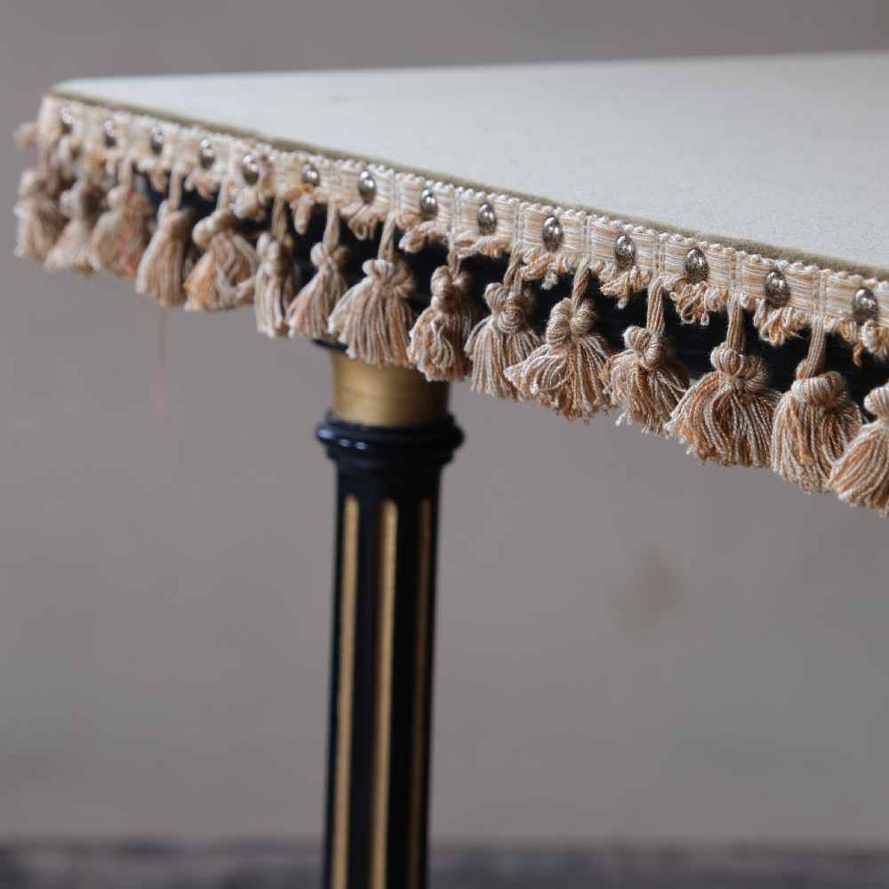 An Aesthetic Movement ebonised and parcel-gilt square table featuring fluted turned legs, a tassel fringe skirt, and brass castors. View XVII
