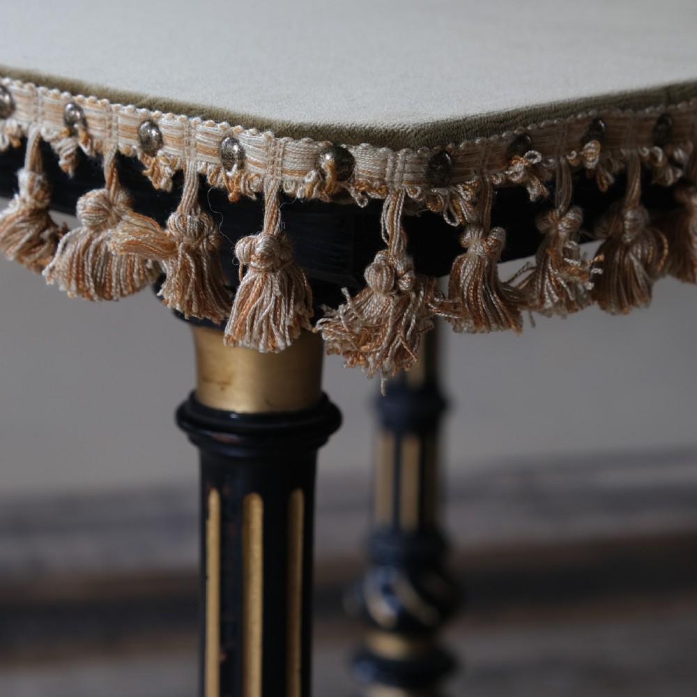 An Aesthetic Movement ebonised and parcel-gilt square table featuring fluted turned legs, a tassel fringe skirt, and brass castors. View XVIII