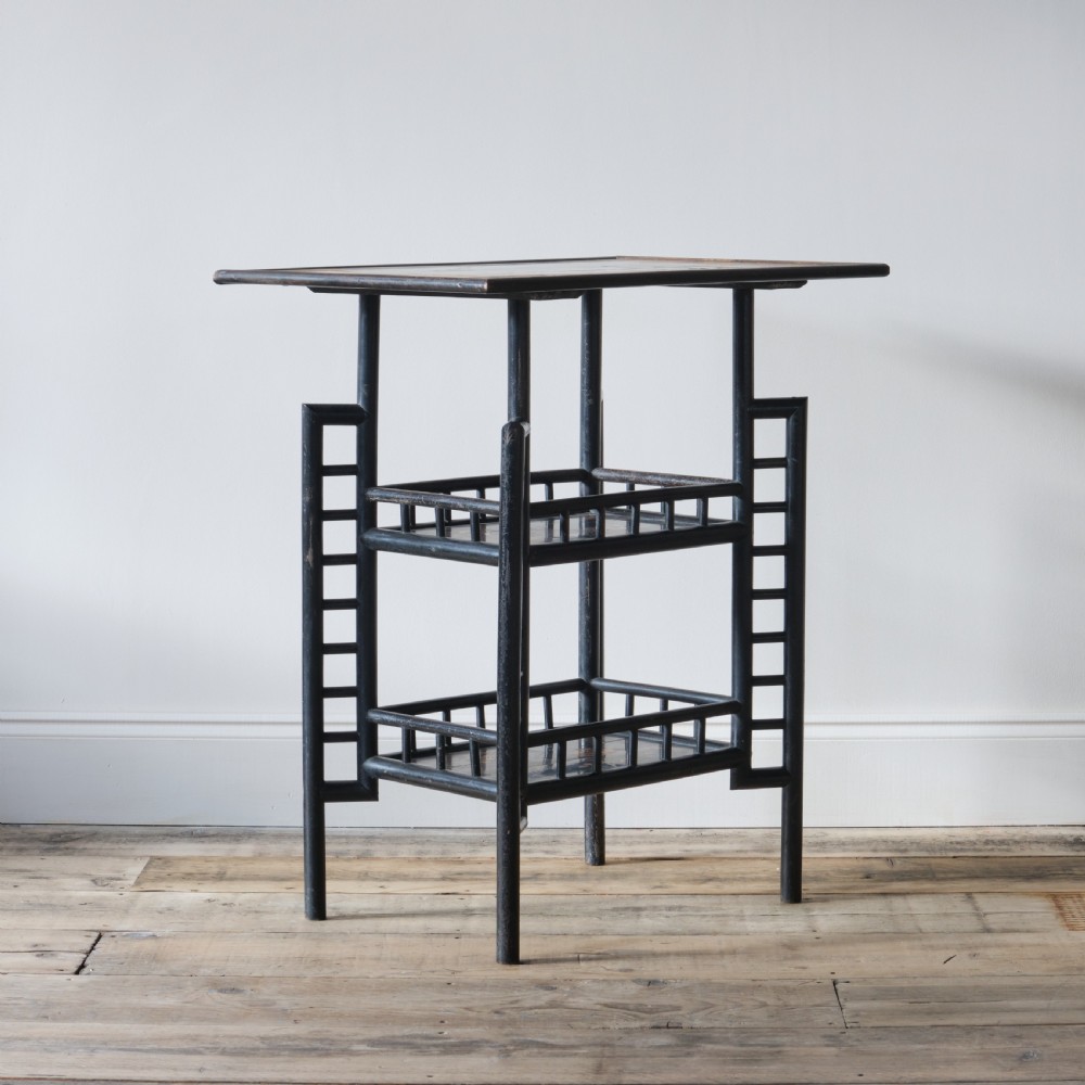 A Victorian Anglo-Japanese ebonised black lacquered three-tier side table featuring lattice side panels and spindled shelf galleries. View VI