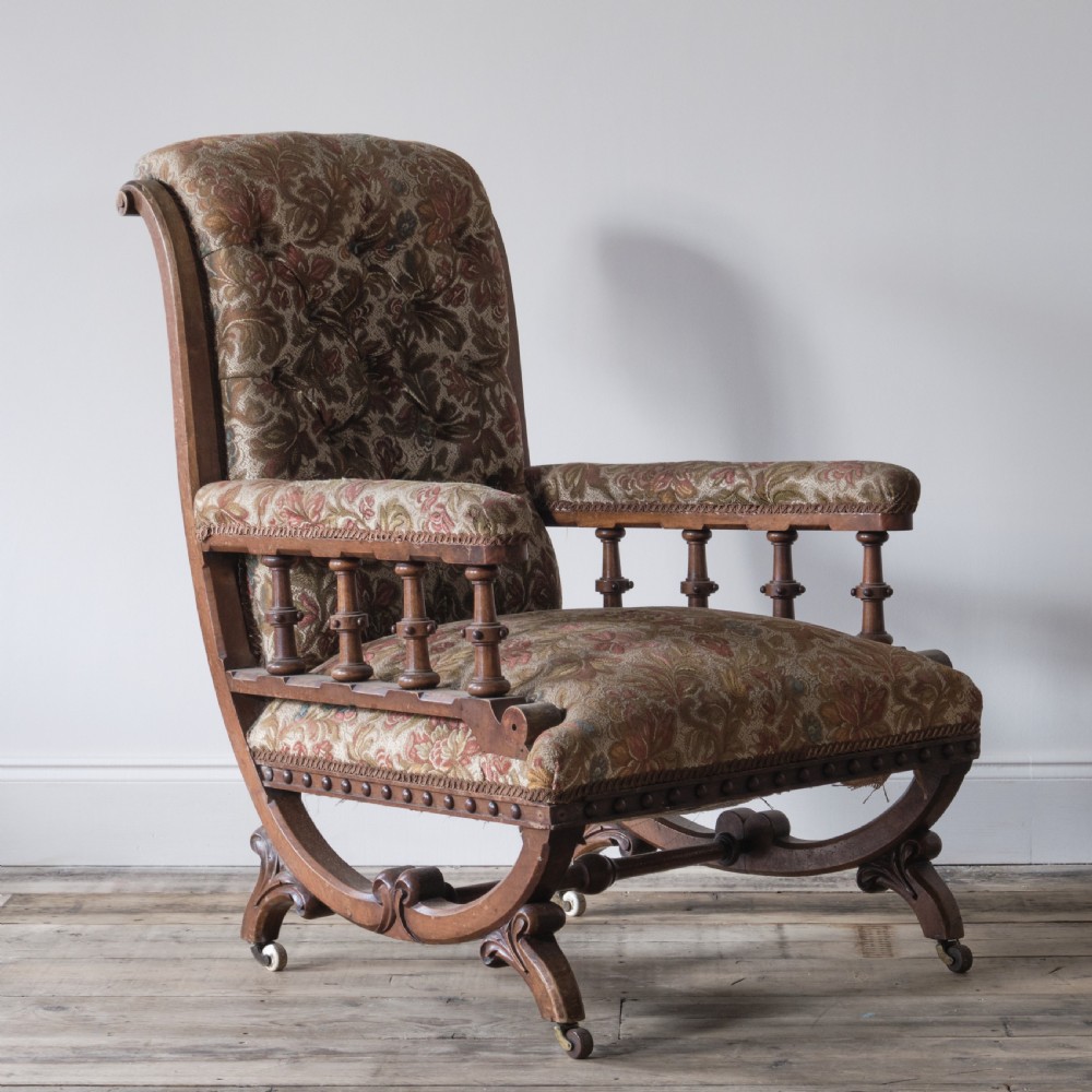 A profile view of a 19th-century Gothic Revival open armchair with a carved walnut frame, turned spindles under padded armrests, and floral tapestry upholstery. View II