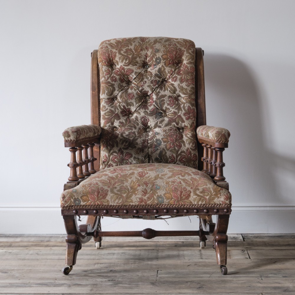 A profile view of a 19th-century Gothic Revival open armchair with a carved walnut frame, turned spindles under padded armrests, and floral tapestry upholstery. View III