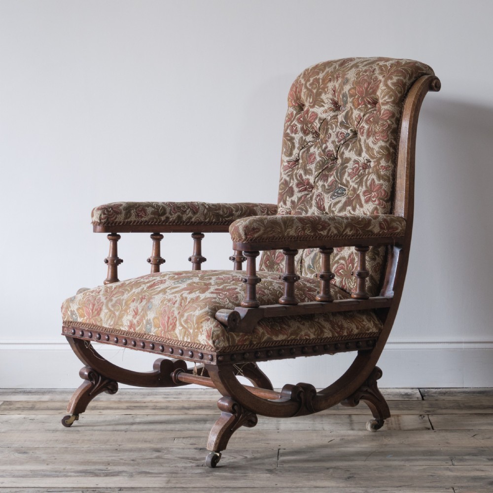 A profile view of a 19th-century Gothic Revival open armchair with a carved walnut frame, turned spindles under padded armrests, and floral tapestry upholstery. View IV