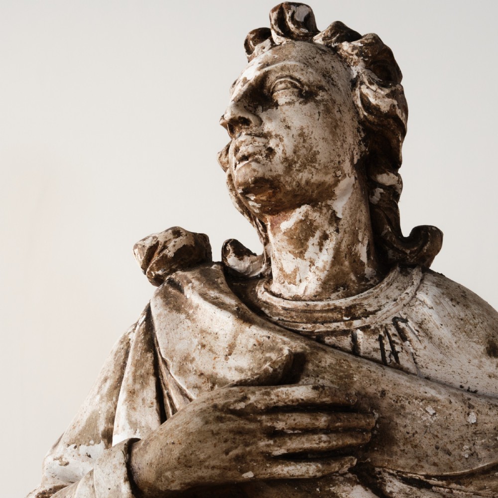 A large freestanding ecclesiastical plaster statue of a saint wearing draped robes, resting on a square pedestal with a distressed brown patinated surface. View III