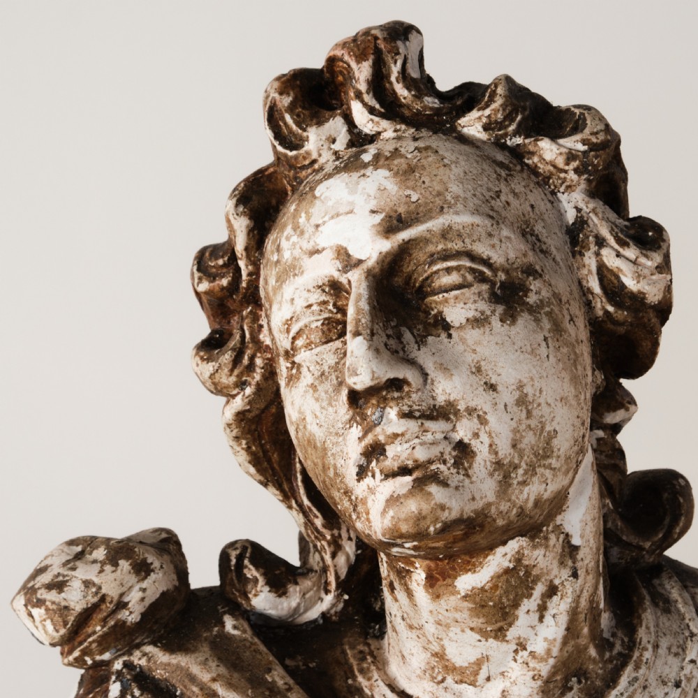 A large freestanding ecclesiastical plaster statue of a saint wearing draped robes, resting on a square pedestal with a distressed brown patinated surface. View VII