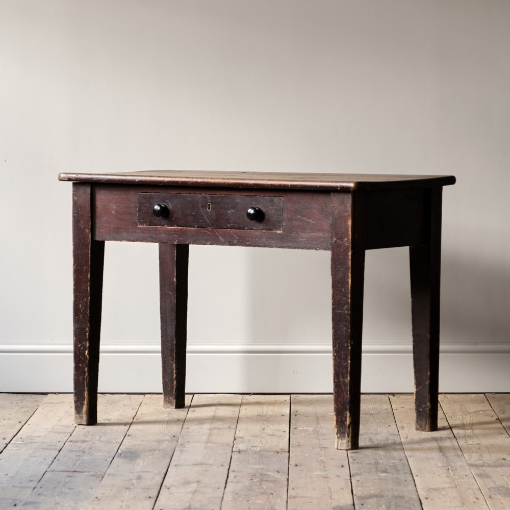 A nineteenth-century dark brown pine side table featuring a single drawer with two black turned wooden knobs and tapered square legs.