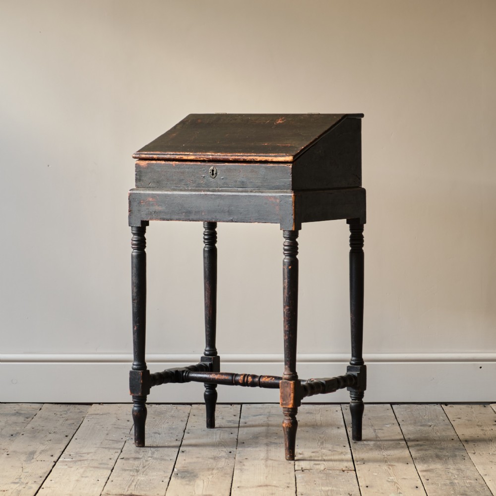 A 19th-century ebonised pine standing clerks desk featuring a slanted hinged lid, turned legs, and an H-stretcher base.
