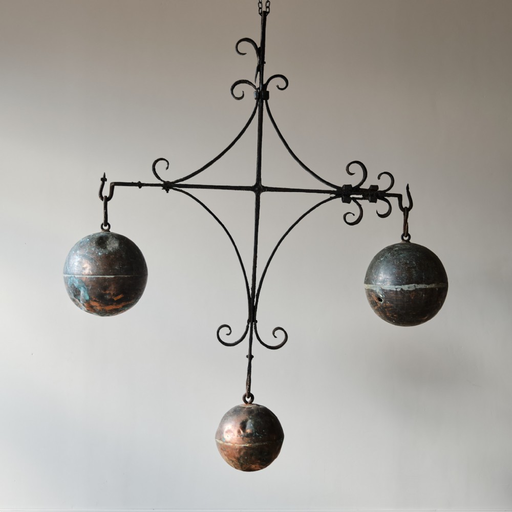 A 19th-century wrought iron framework featuring scrollwork and supporting three suspended copper spheres.