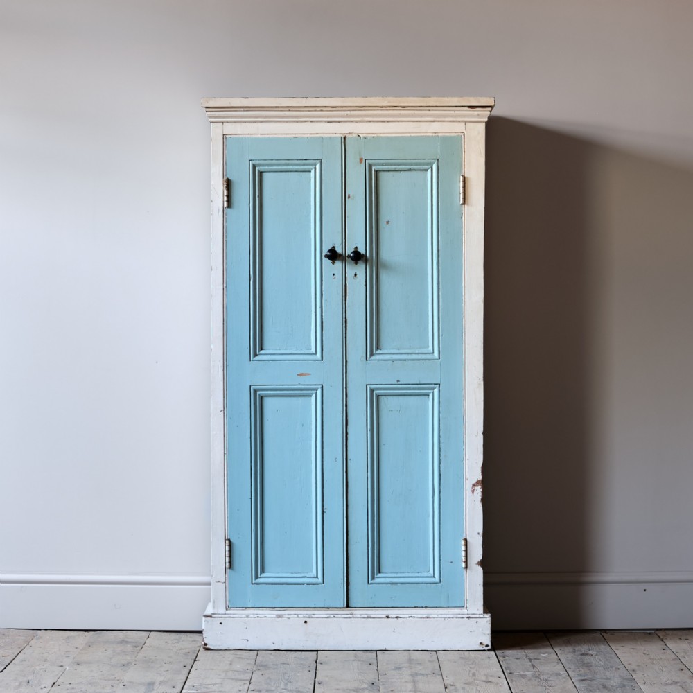 A 19th-century painted pine housekeepers cupboard with duck egg blue recessed panel doors framed by a cream-painted casing.