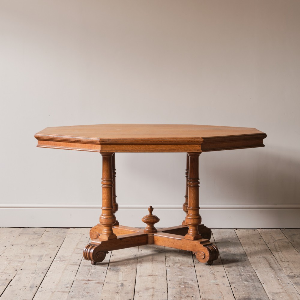 A 19th-century oak centre table featuring an octagonal top supported by four turned legs and an X-shaped cross-stretcher with a central finial.