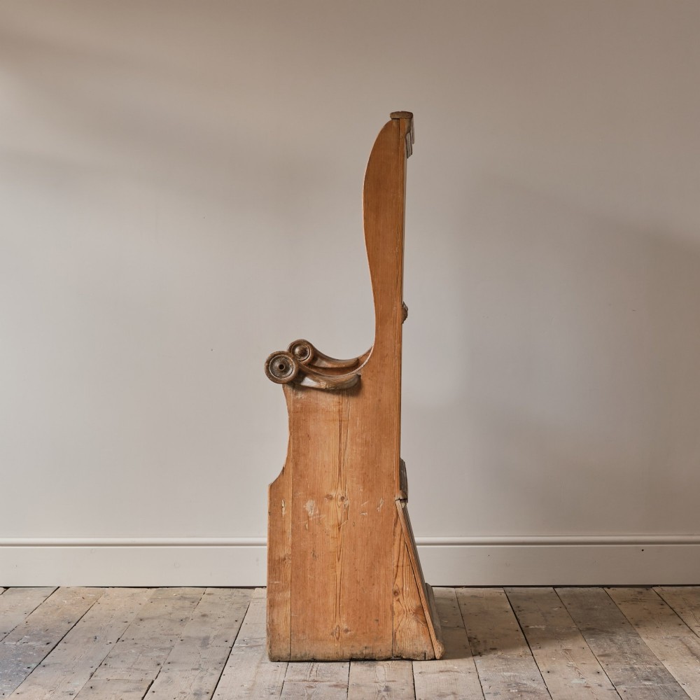 A 19th-century pine and elm high-backed settle featuring scrolled armrests and vertical plank construction. View V