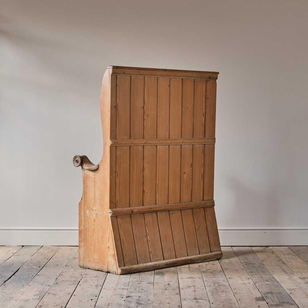 A 19th-century pine and elm high-backed settle featuring scrolled armrests and vertical plank construction. View VI