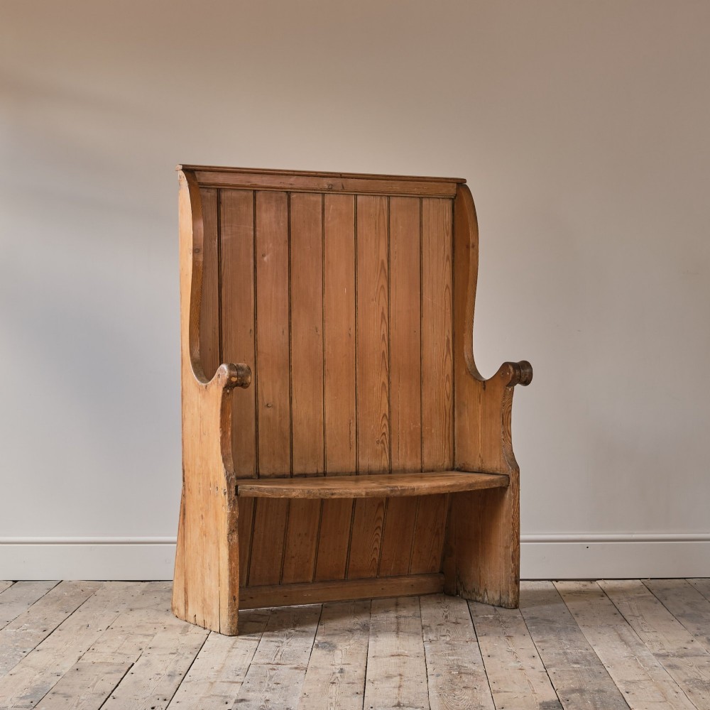 A 19th-century pine and elm high-backed settle featuring scrolled armrests and vertical plank construction. View X