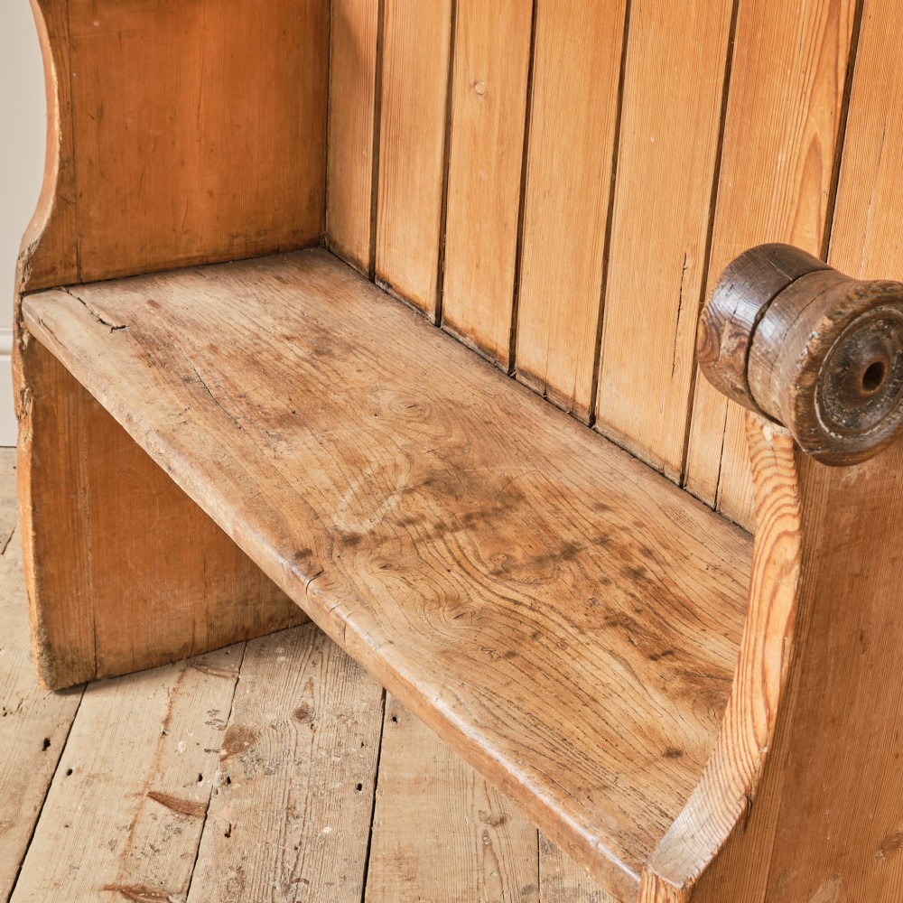 A 19th-century pine and elm high-backed settle featuring scrolled armrests and vertical plank construction. View XII