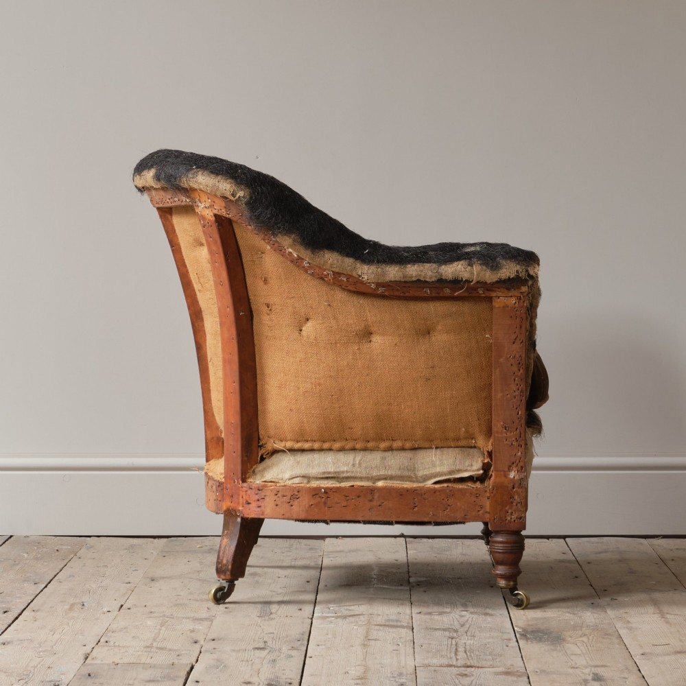 A 19th-century Howard and Sons Pickwell tub armchair showing exposed original hessian, horsehair filling, a brown velvet seat cushion, turned wooden legs, and brass castors. View VII