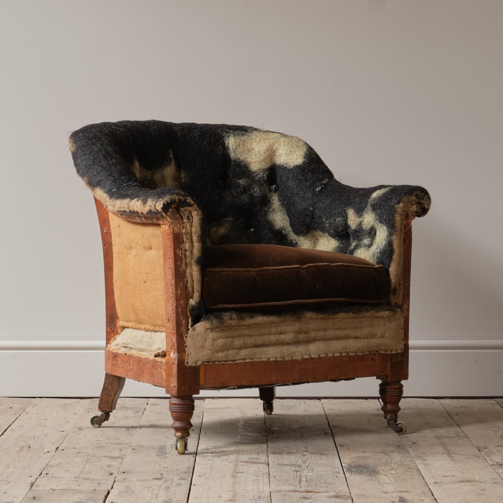 A 19th-century Howard and Sons Pickwell tub armchair showing exposed original hessian, horsehair filling, a brown velvet seat cushion, turned wooden legs, and brass castors. View VIII