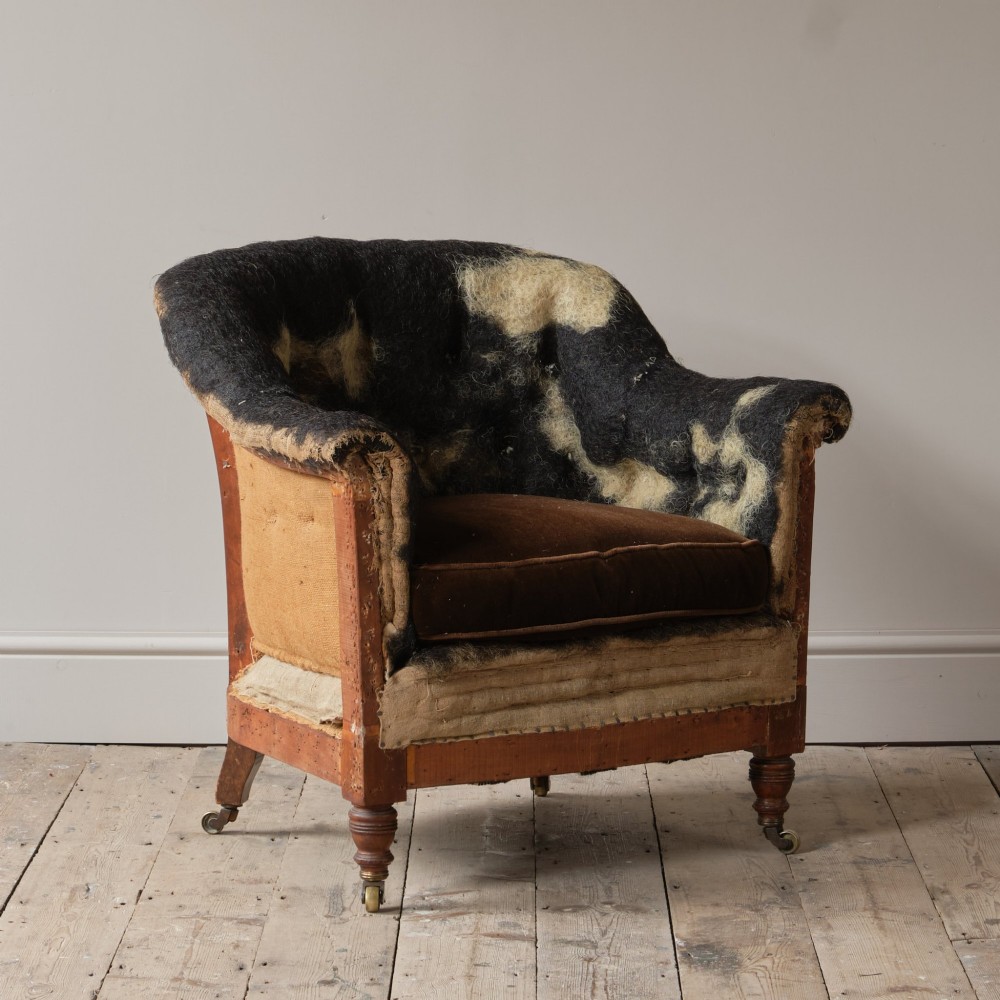 A 19th-century Howard and Sons Pickwell tub armchair showing exposed original hessian, horsehair filling, a brown velvet seat cushion, turned wooden legs, and brass castors. View IX