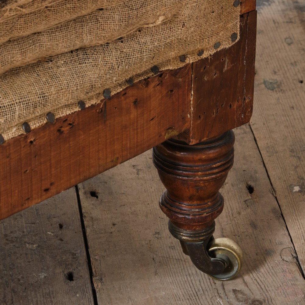 A 19th-century Howard and Sons Pickwell tub armchair showing exposed original hessian, horsehair filling, a brown velvet seat cushion, turned wooden legs, and brass castors. View X