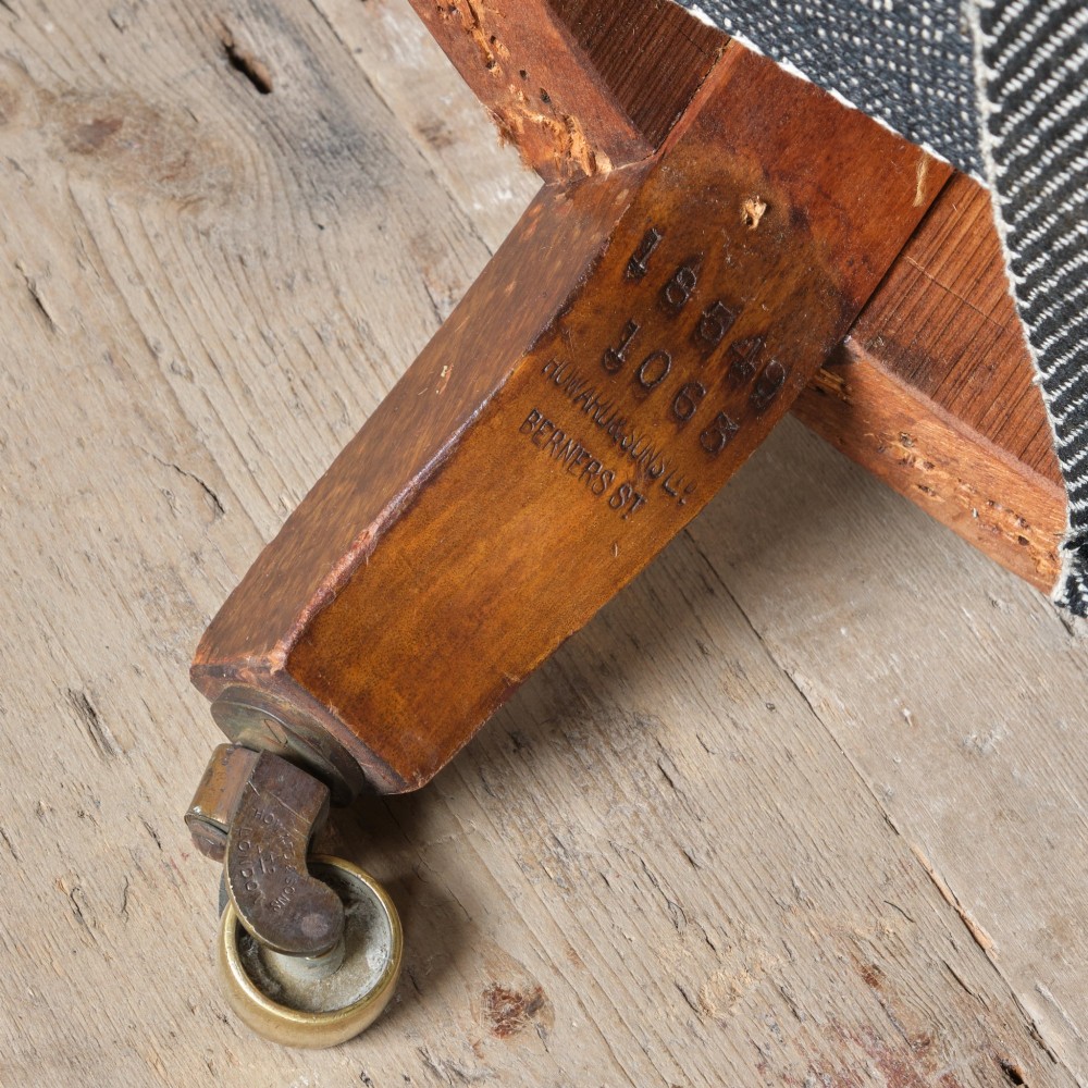 A 19th-century Howard and Sons Pickwell tub armchair showing exposed original hessian, horsehair filling, a brown velvet seat cushion, turned wooden legs, and brass castors. View XII