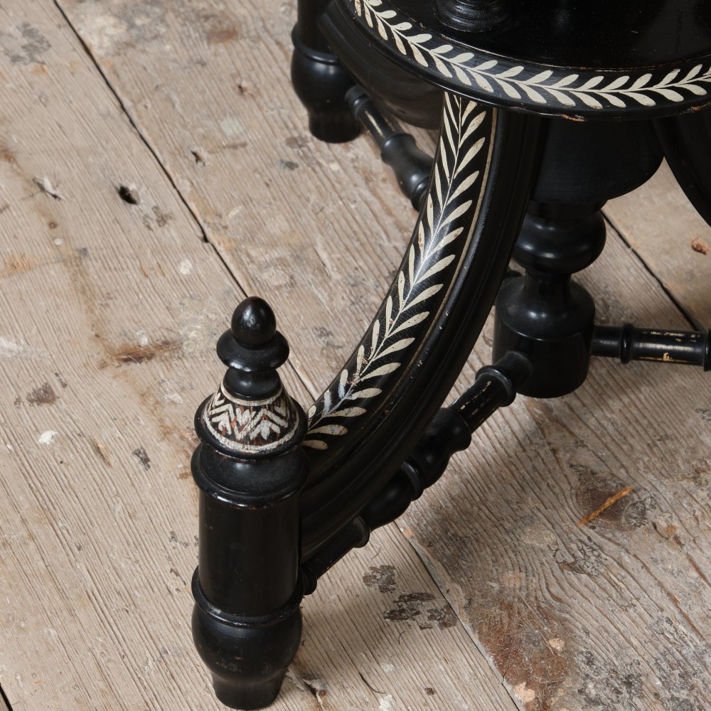 A 19th-century Aesthetic Movement ebonised tripod side table featuring a circular top, turned central column, light-coloured decorative inlay, and finial details. View V