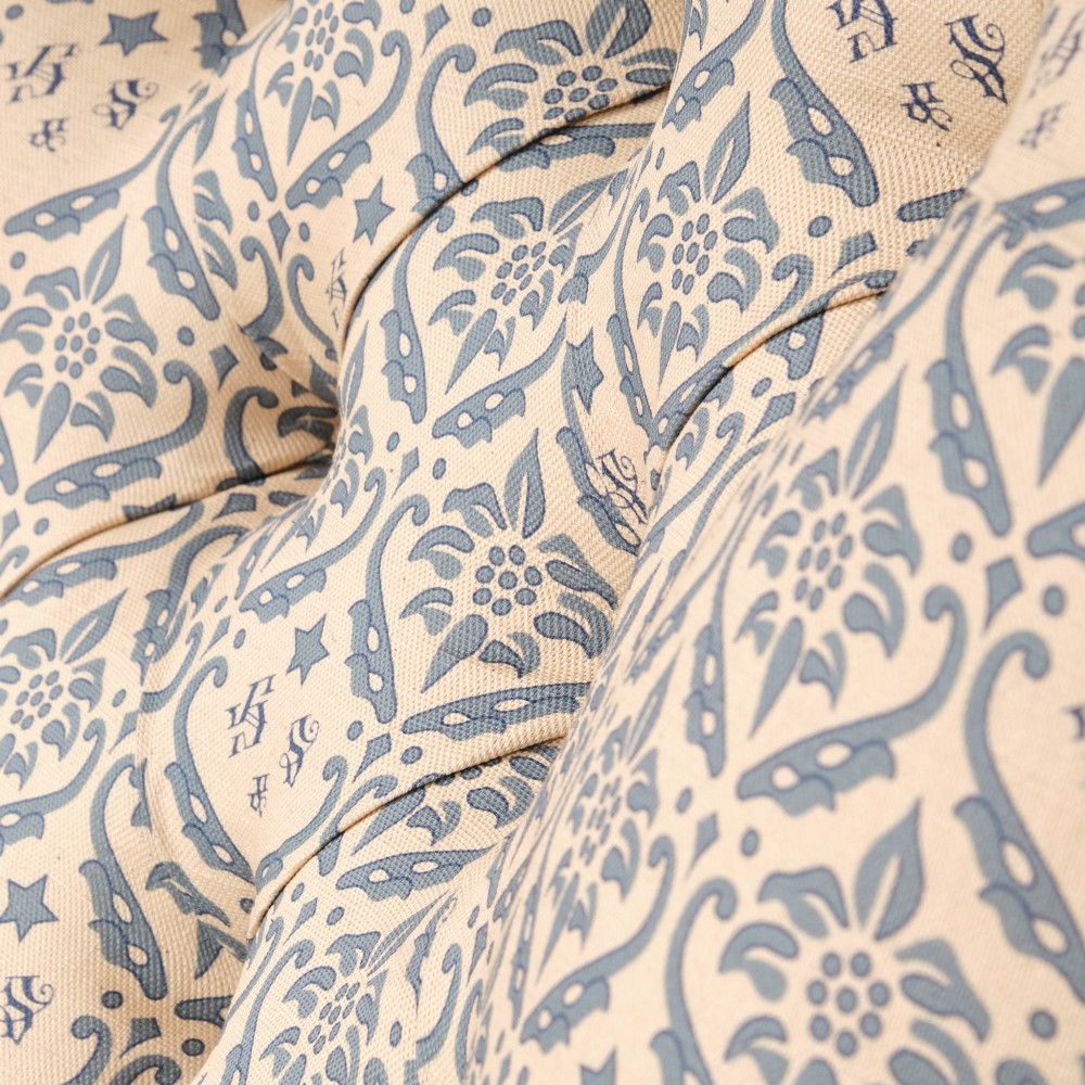 A mid-19th century Victorian upholstered armchair featuring blue and cream patterned fabric, deep button-tufted backrest, turned wooden front legs, and brass castors. View VII