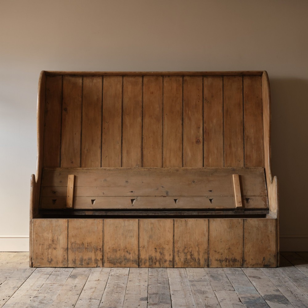 An early nineteenth-century Georgian pine high-backed settle featuring winged side panels and a planked box base. View III