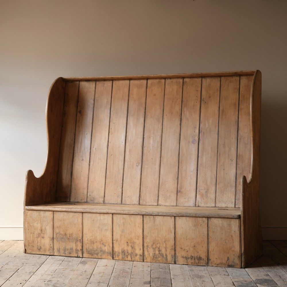 An early nineteenth-century Georgian pine high-backed settle featuring winged side panels and a planked box base. View IV
