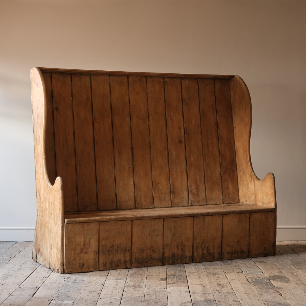 An early nineteenth-century Georgian pine high-backed settle featuring winged side panels and a planked box base. View XV